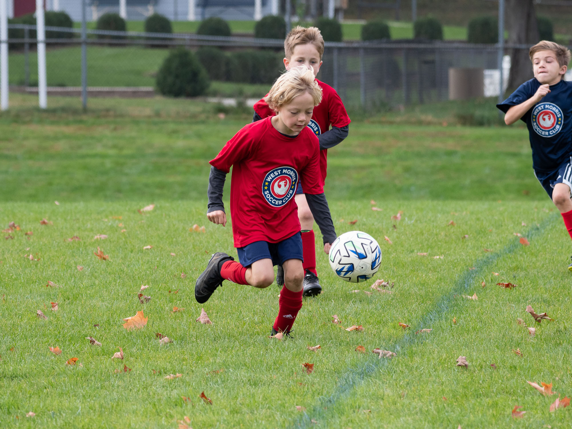 West Morris player chasing ball through autumn leaves